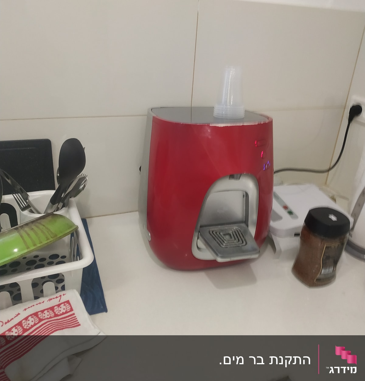 מכונת קפה אדומה עם כוסות פלסטיק על השיש